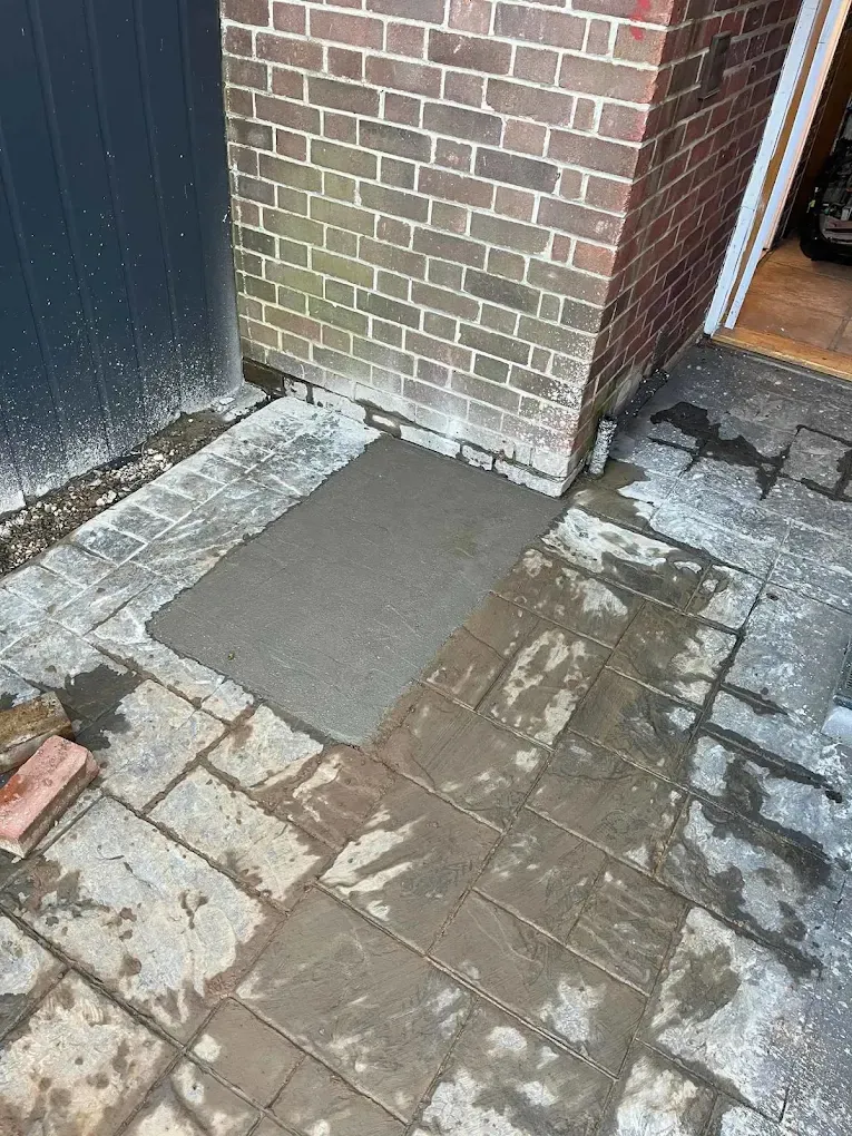 A square of fresh concrete laid neatly into the paving outside a back door